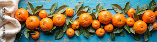 Fresh oranges and leaves on blue wooden background