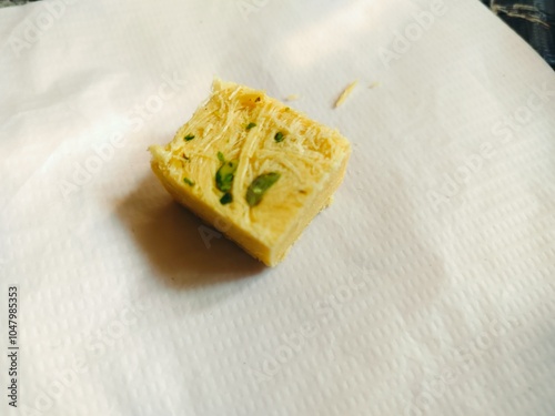 Single piece of soan papdi on white background. Soan papdi is a famous sweet of india. It's made of gram flour (besan), sugar, ghee and milk. Yellow piece of sweet  photo