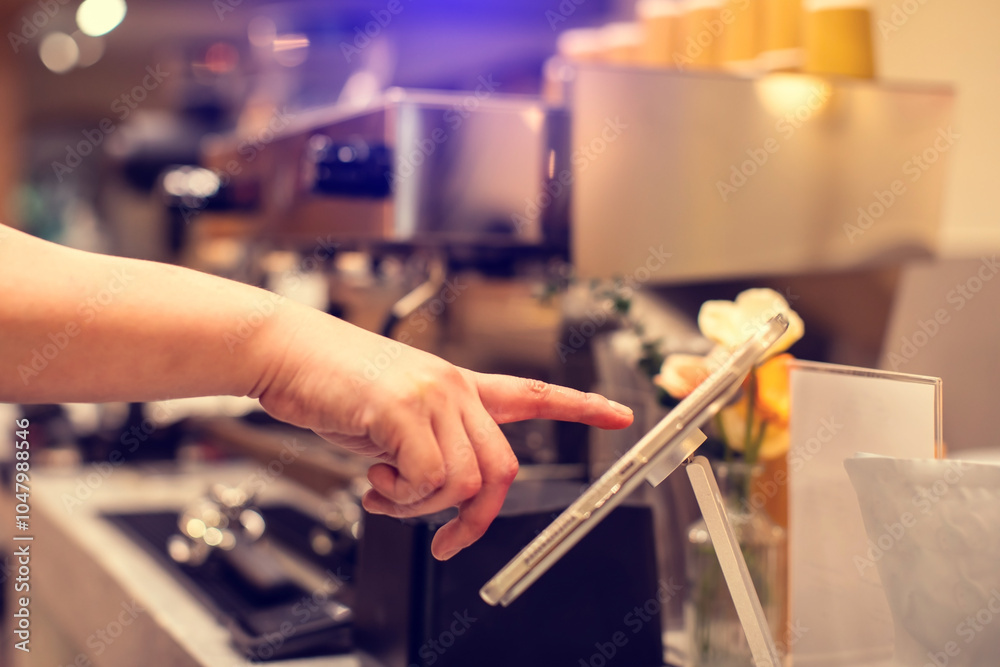 Cashier staff using tablet to receive orders from customers at counter service in cafe or store. Cashier takes payment from customer with digital tablet.