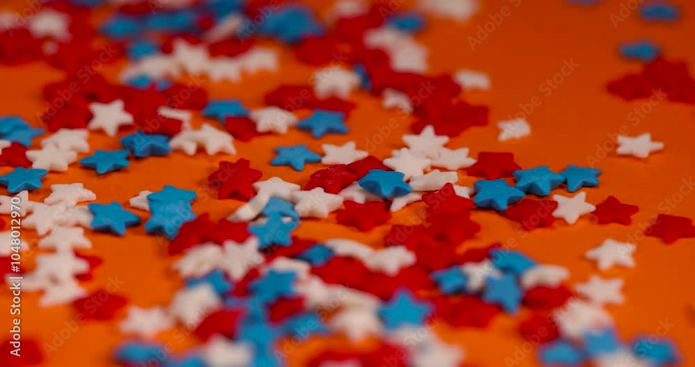   sugar candies in the shape of a star, red white and blue sugar candies for decoration on an orange background