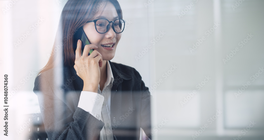 Talking on mobile phone. Close up, smiling asian business woman with eyeglasses using mobile phone, talking to customer during working at office, talking on phone solving business issues Talking on mobile phone. Close up, smiling asian business woman with eyeglasses using mobile phone, talking to customer during working at office, talking on phone solving business issues
