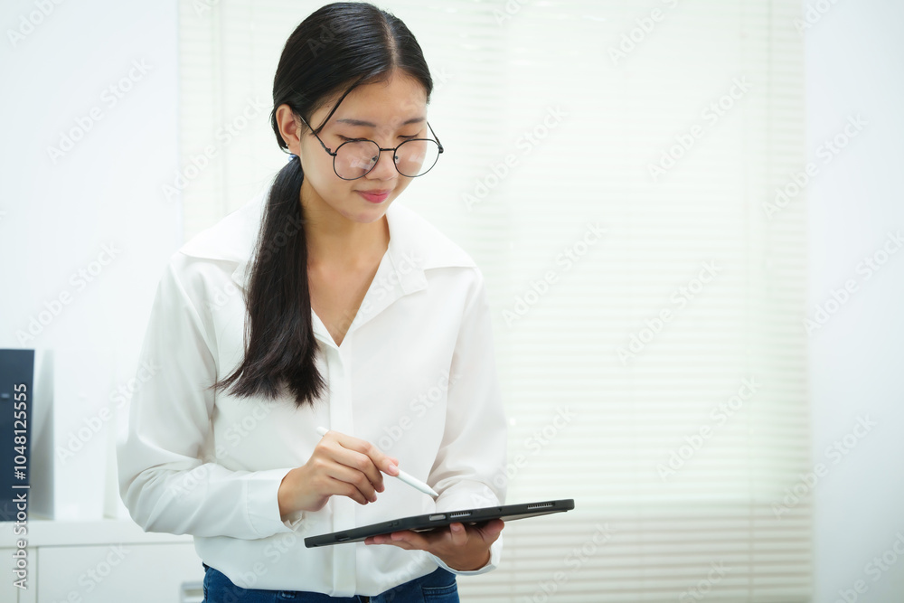 An Asian businesswoman smiles confidently while working at her desk in the office. She diligently analyzes financial data on her laptop, showcasing her expertise and commitment as an accountant An Asian businesswoman smiles confidently while working at her desk in the office. She diligently analyzes financial data on her laptop, showcasing her expertise and commitment as an accountant