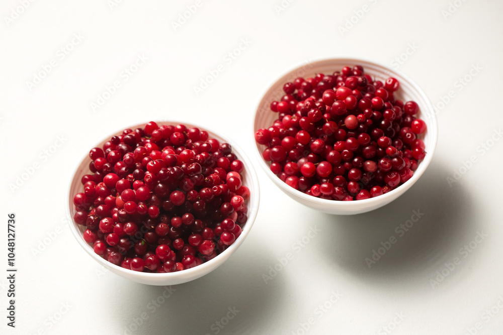 Two bowls of lingonberries on a white background Two bowls of lingonberries on a white background