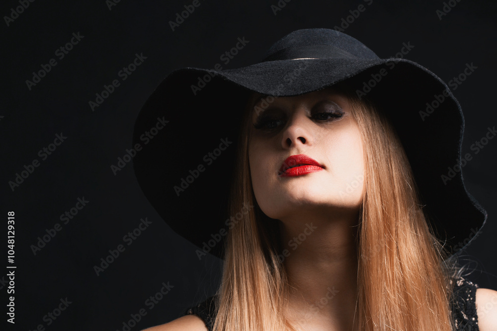 A woman wearing a black hat. The mysterious expression of the face is covered by the wide brim of the hat A woman wearing a black hat. The mysterious expression of the face is covered by the wide brim of the hat