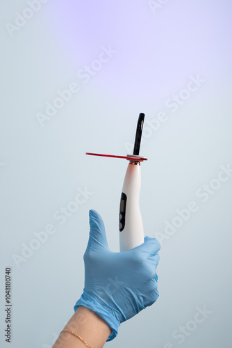 Dental assistant holding a curing light for dental procedures in a modern clinic during an appointment