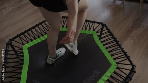Woman exercising on a sports trampoline at home, focusing on fitness and fun. The trampoline setup is ideal for indoor workouts and healthy living.