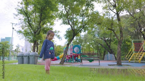 Adorable little 3 -4 year asian preschool girl enjoying run on green meadow city paublic park photo