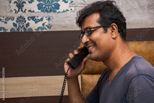 Young Man Talking on a Landline Phone at Home