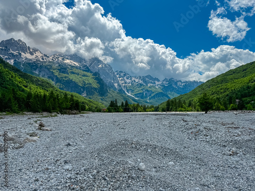 Vast field of rocks from dried riverbank with vista on majestic mountain massif Zhaborret, Albanian Alps (Accursed Mountains), Valbone Valley National Park, Albania. Wanderlust in alpine wilderness photo