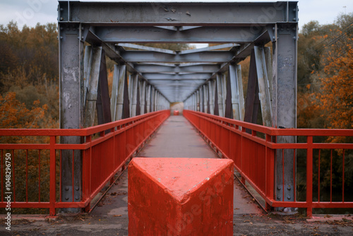 Pedestrian bridge over the river made of iron beams and with a red fence photo