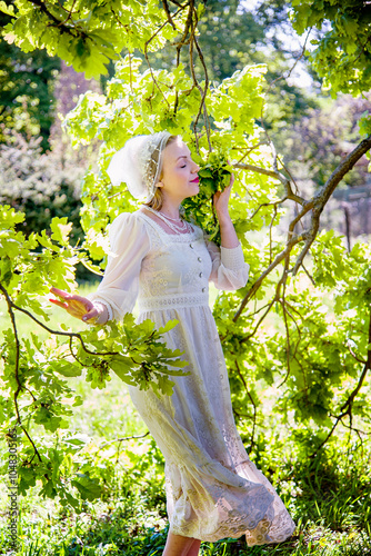 portrait of beautiful blonde smiling   woman in vintage white dress and mutch  touching lilac flowers in the summer garden. Wedding day photo