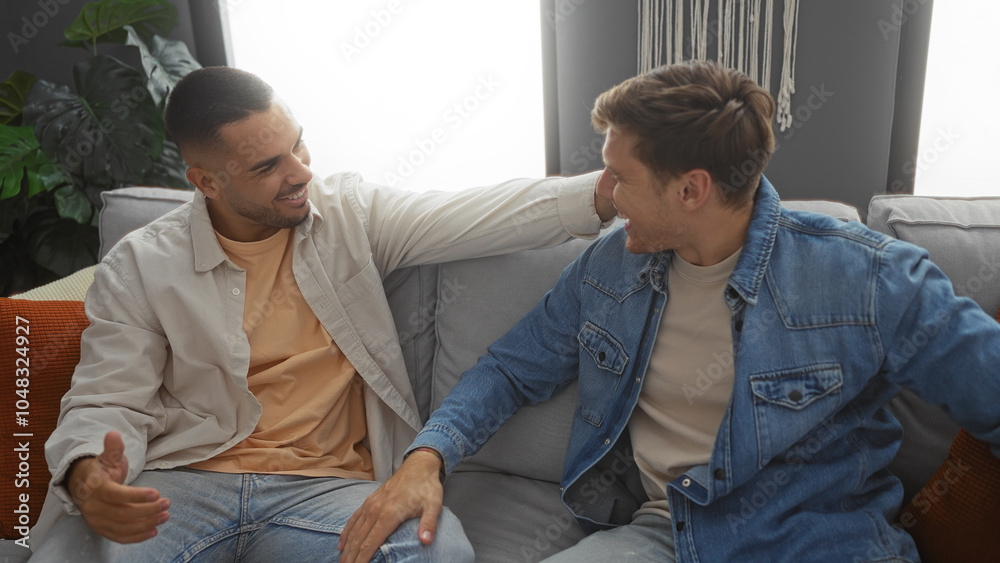 Fototapeta premium Men friends laughing together on a cozy couch in a modern apartment living room enjoying an indoor relaxed moment