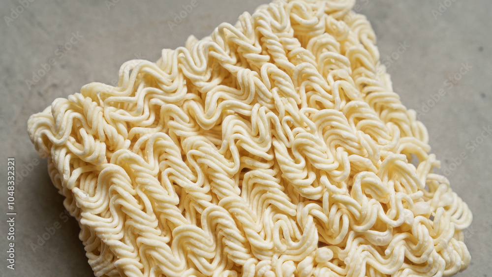 Dried ramen noodles closeup on a textured grey surface highlighting food detail and texture. Dried ramen noodles closeup on a textured grey surface highlighting food detail and texture.