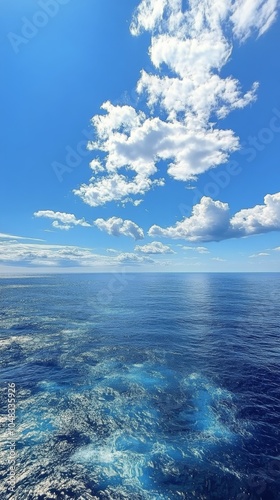 Clear blue water reflecting fluffy clouds over a calm ocean during a bright s...