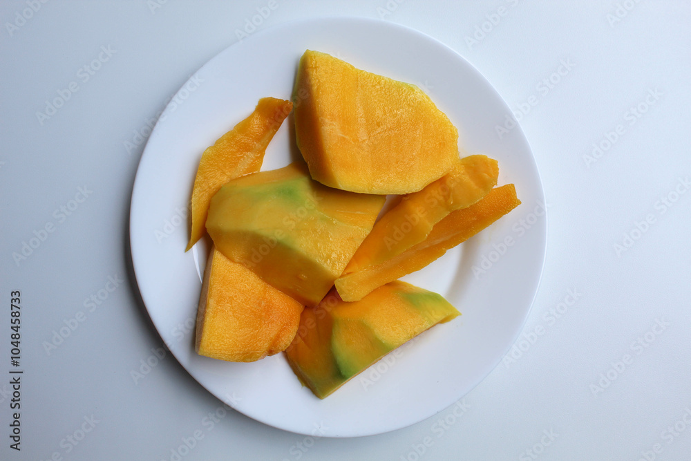 Fresh yellow mango slices, on white plate, isolated on white background, flat lay or top view Fresh yellow mango slices, on white plate, isolated on white background, flat lay or top view