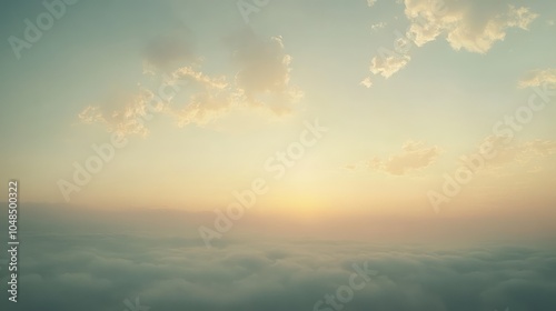 A moody hazy sky with deep gray clouds merging with soft peach hues as the sun sets, casting a faint glow over the landscape