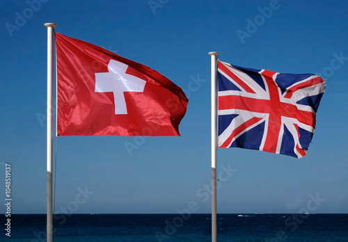 The national flags of Switzerland and the United Kingdom next to the sea
