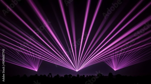 The image shows a crowd silhouetted in front of three purple lasers, creating a dramatic and vibrant scene.