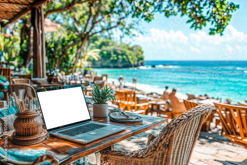 Ecran blanc d'ordinateur portable sur une terrasse de restaurant devant la mer photo