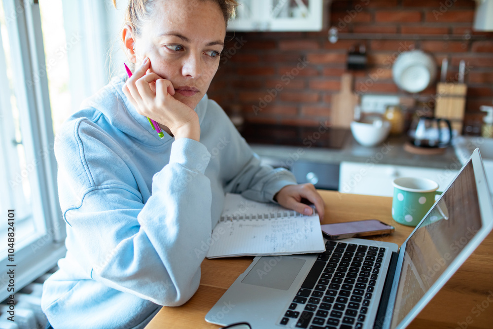 © Davor - Young woman working on laptop at home