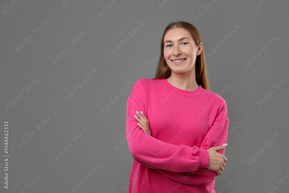 Obraz premium Smiling girl with braces on grey background, space for text