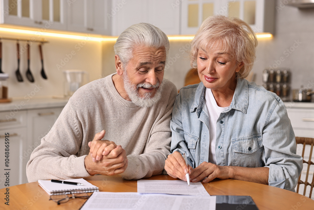 Pension savings. Senior couple planning budget at wooden table indoors Pension savings. Senior couple planning budget at wooden table indoors