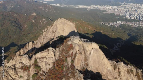 drone shot of a mountain summit with huge rocks with the city in the background