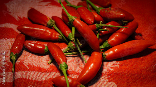 фотографія Chili pepper, red ripe pepper on red tablecloth, hot spices, calabrian hot peppe
