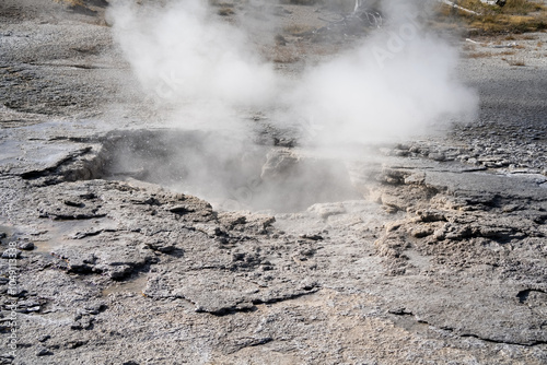 an active geyser spring with an intermittent discharge of water ejected turbulently and accompanied by steam photo