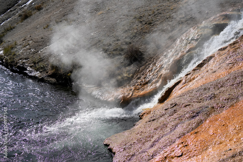 an active geyser spring with an intermittent discharge of water ejected turbulently into a river photo