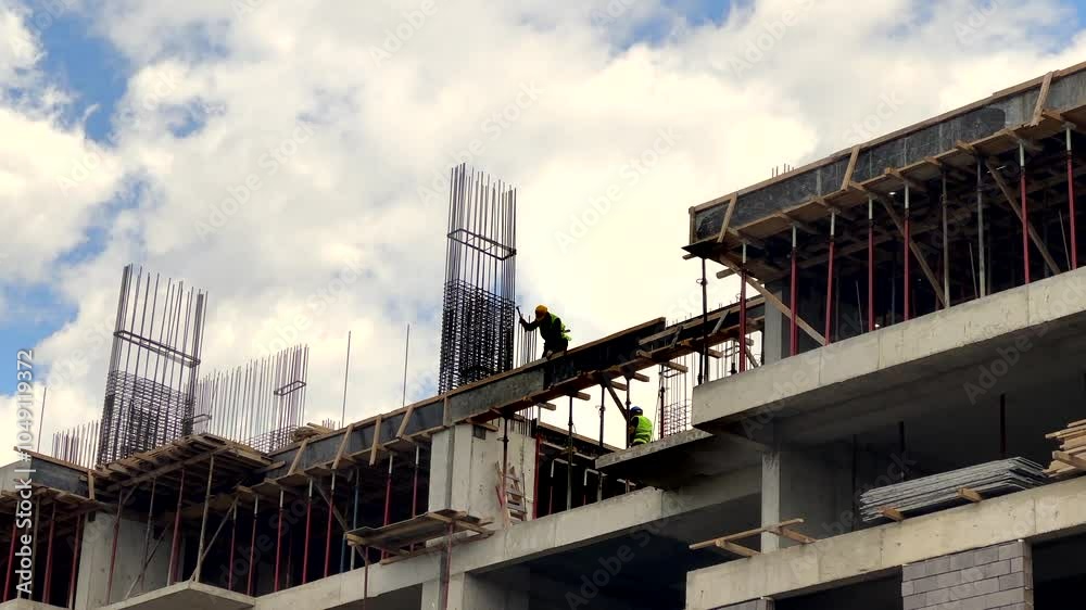 Silhouetted construction workers in construction site over sky
