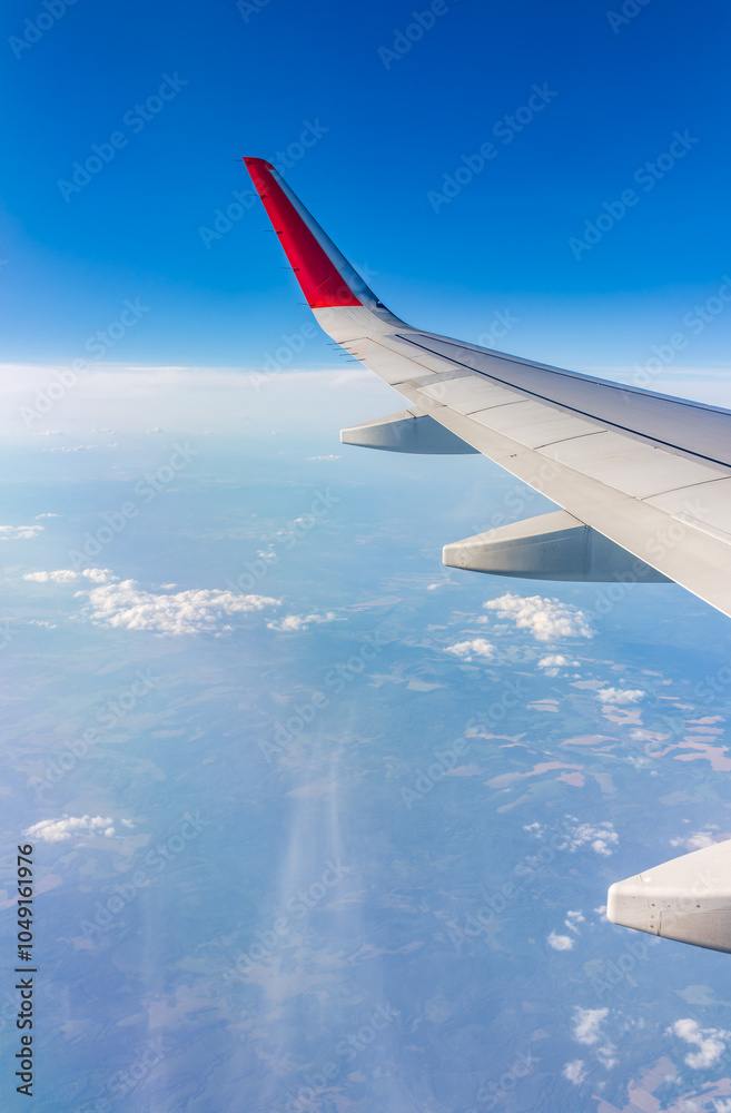 Fototapeta premium View from the airplane window at a beautiful cloudy sky and the airplane wing