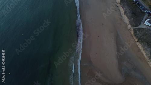 Camera glides forward from Playa América to Panxón, capturing people strolling along the beach. Miñor River mouth, dunes and Panxón's illuminated seaside promenade, where people enjoy an evening walk.