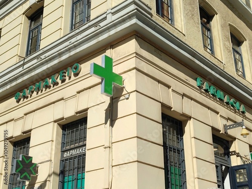 Corner view of an apothecary store in Piraeus, Greece, combining Greek and Italian signage along with the characteristic green cross symbol. photo