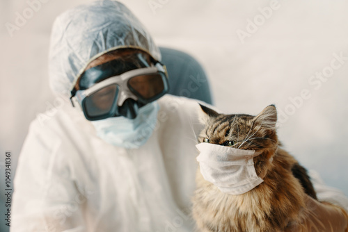 Both a person and a cat are seen wearing masks and protective gear for safety and health measures during the pandemic