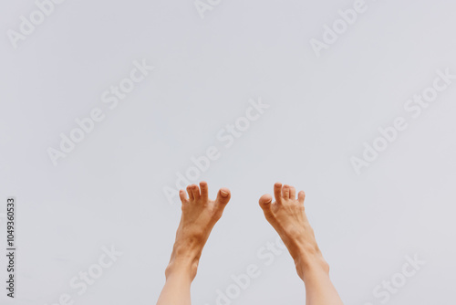 Person's bare feet in the air against a blue sky background