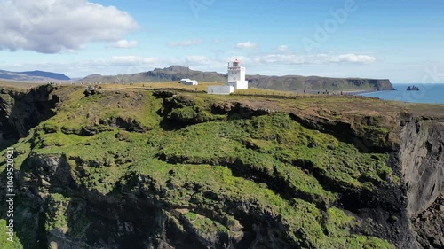 Aerial view of a lighthouse on a rock on the ocean shore in Iceland. A beautiful landscape of nature, cliffs washed by the ocean, tourism and travel. High quality 4k footage photo