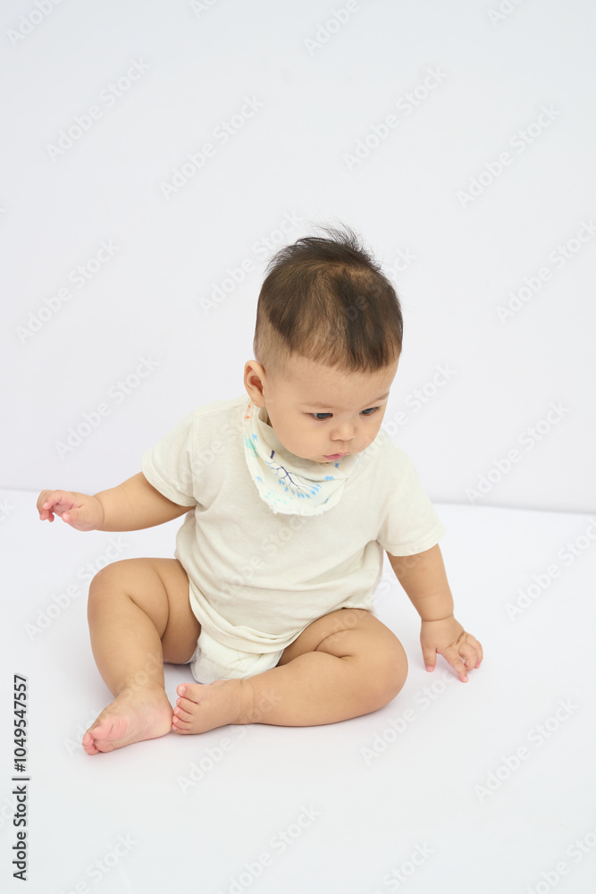 Fototapeta premium A Baby Sitting on the Floor with saliva towels under the chin