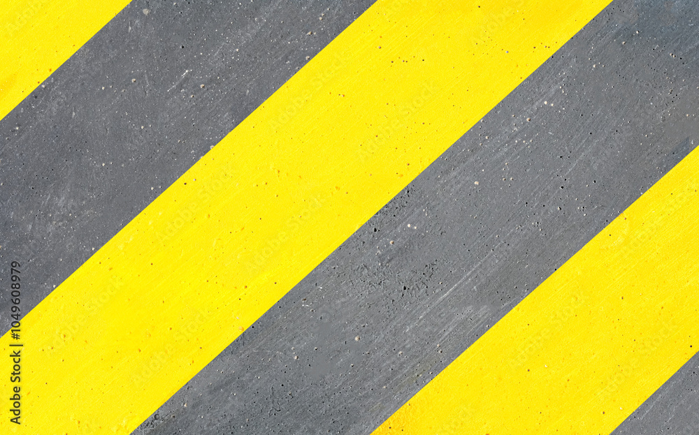 Fototapeta premium The cement wall painted in alternating yellow and black at an angle serves as a warning sign.