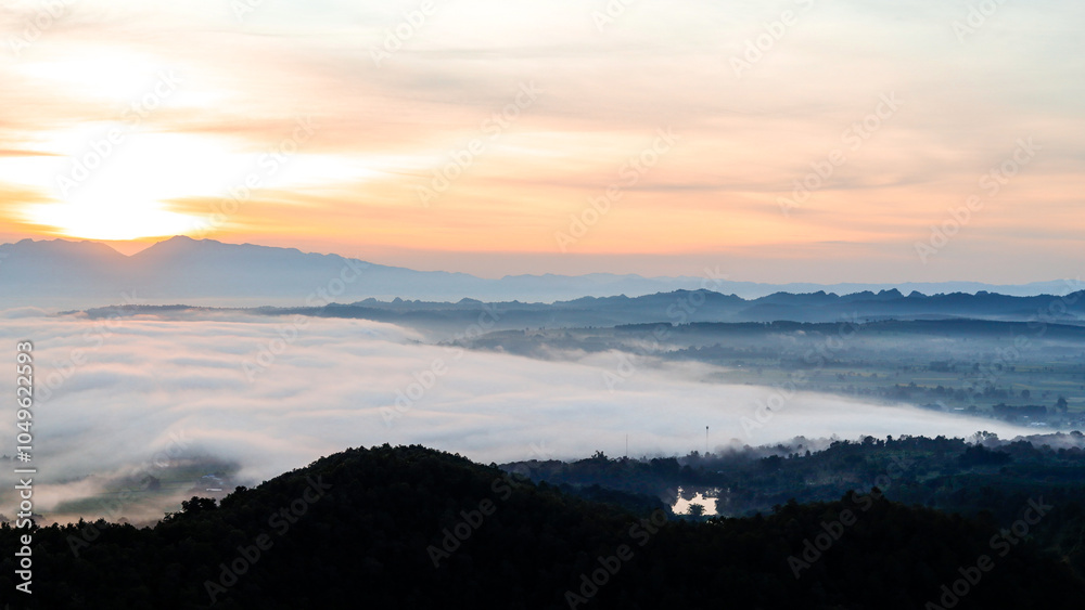 A high-altitude landscape shot showing the morning mist covering the entire city and the sunrise.