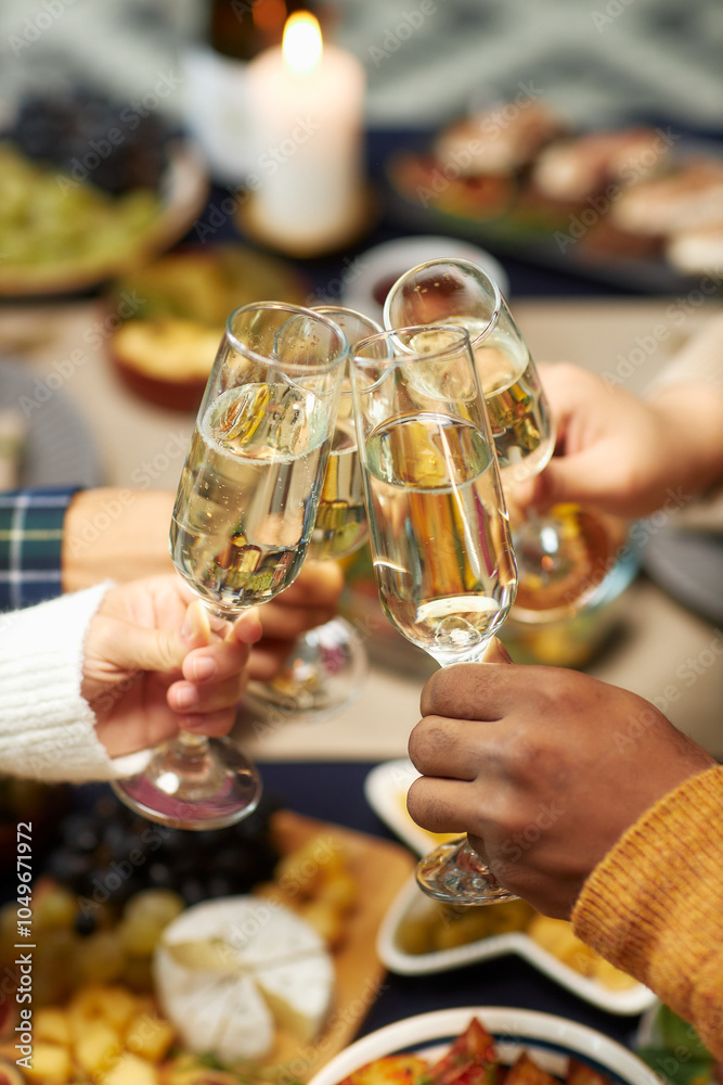 © Seventyfour - Vertical shot of hands of people raising toast clinking glasses with champagne celebrating Christmas together at home party, copy space