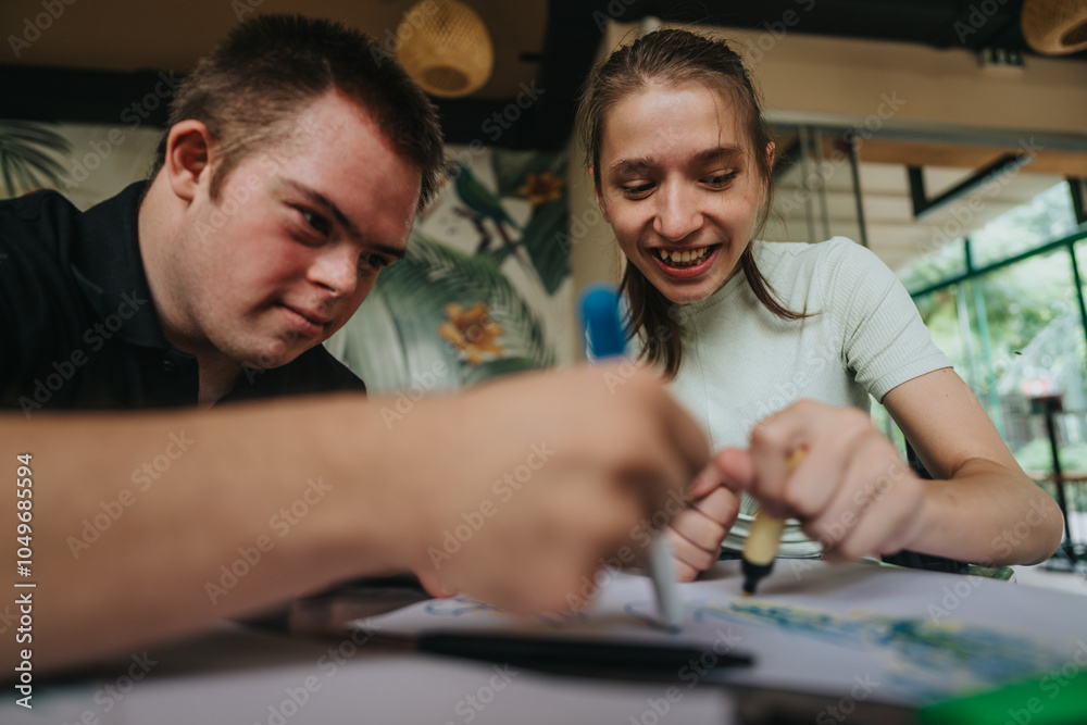 A young male with Down syndrome and a girl in a wheelchair joyfully engage in a creative painting session together, showcasing friendship and inclusion. A young male with Down syndrome and a girl in a wheelchair joyfully engage in a creative painting session together, showcasing friendship and inclusion.