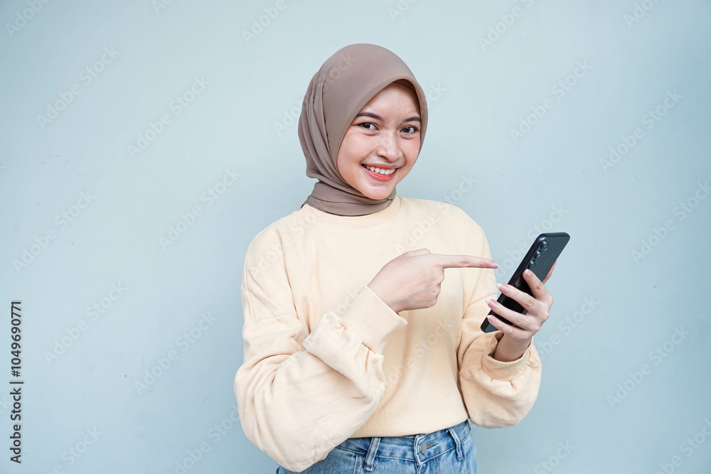 Cheerful beautiful Asian muslim woman in cream sweater using mobile phone, received good news on social media isolated over white background. People religious lifestyle concept. Cheerful beautiful Asian muslim woman in cream sweater using mobile phone, received good news on social media isolated over white background. People religious lifestyle concept.
