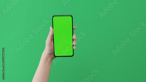 Young woman hand show smartphone with green screen on green background