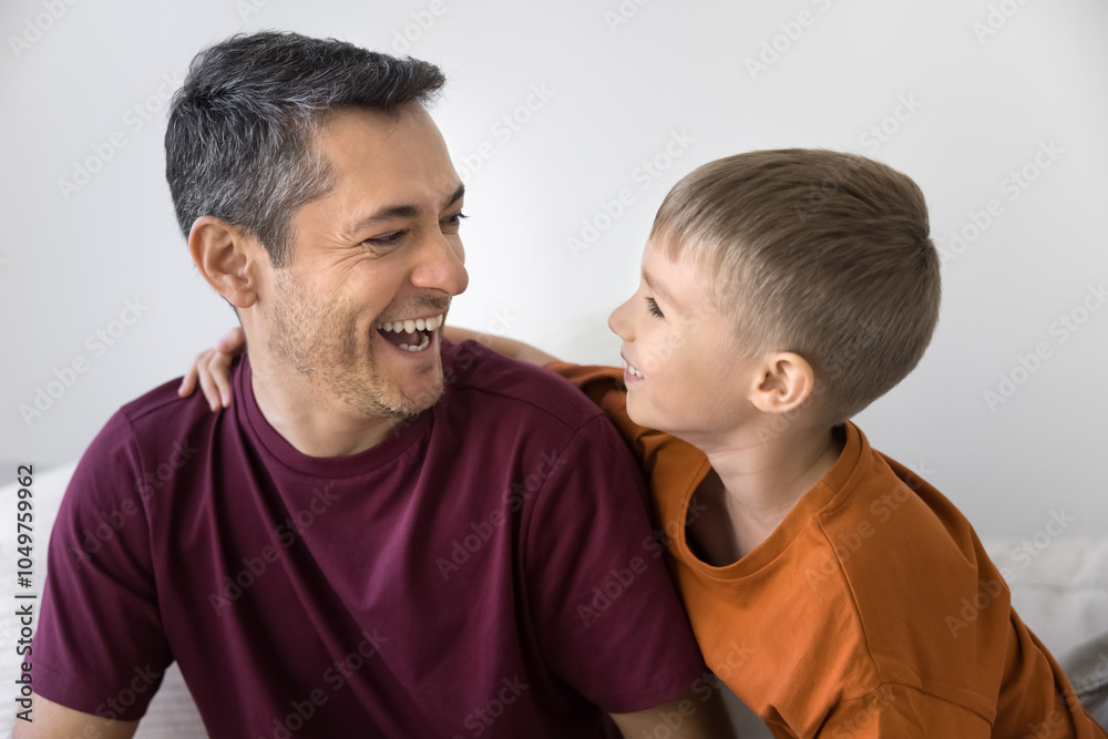 Positive active son kid and cheerful Hispanic daddy playing, hugging, talking and laughing at home, having fun on couch, enjoying family activity, leisure, entertainment, childhood, fatherhood Positive active son kid and cheerful Hispanic daddy playing, hugging, talking and laughing at home, having fun on couch, enjoying family activity, leisure, entertainment, childhood, fatherhood