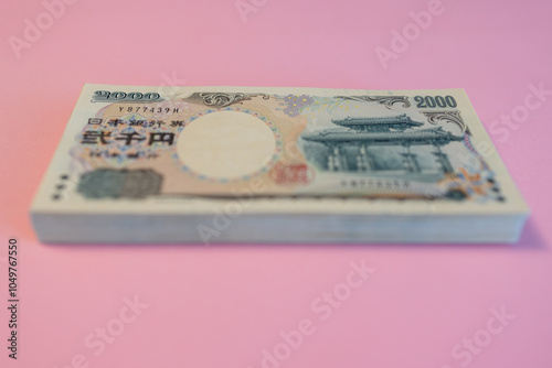 2000 yen banknotes placed against a delicate sakura pink backdrop, symbolizing Japan economic prosperity and the serenity of cherry blossom inspired colors photo