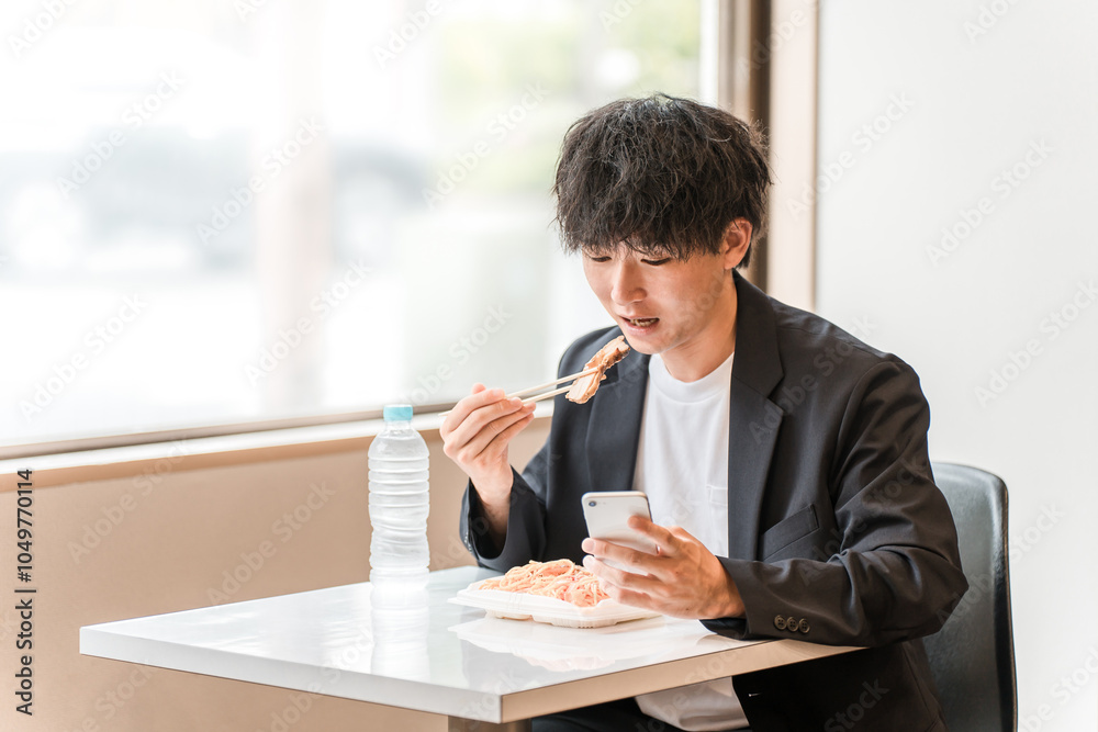 イートインスペースでスマホを見ながら昼食にお弁当を食べる若いアジア人男性ビジネスマン
イートインスペースでスマホを見ながら昼食にお弁当を食べる若いアジア人男性ビジネスマン