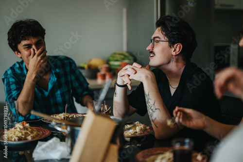 Fotografie Friends gather around a table sharing laughter and pasta dishes, creating a warm and joyful atmosphere