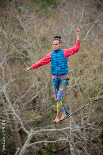 A tightrope walker walks along a cable stretched over a canyon.