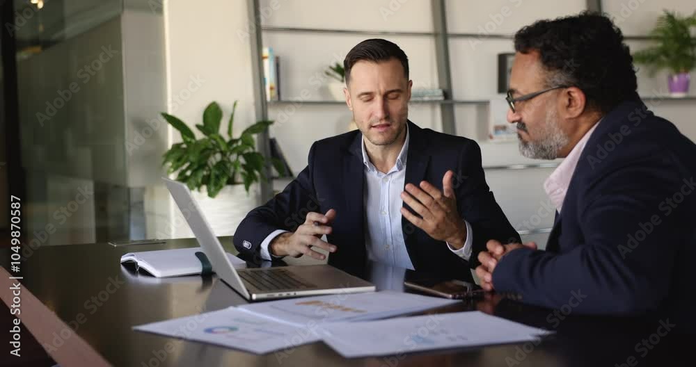 Client and manager presents detailed proposal to client during negotiation process in company office, showing visual data or presentation, provides information, review agreement terms using computer